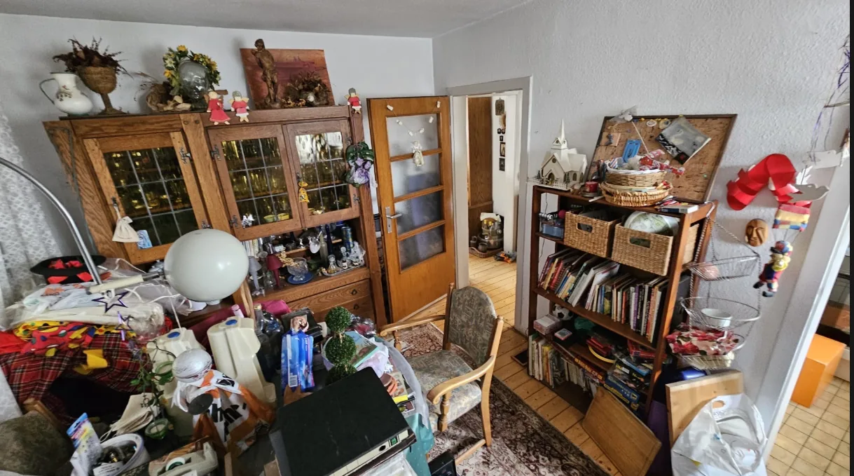 Vollgestelltes Esszimmer mit Vitrine, Regal und Gerümpel vor der Haushaltsauflösung