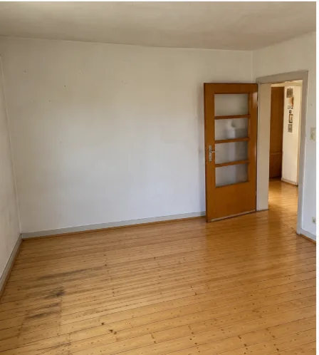 Leeres, besenreines Zimmer mit Holzdielen und offener Tür nach der Haushaltsauflösung