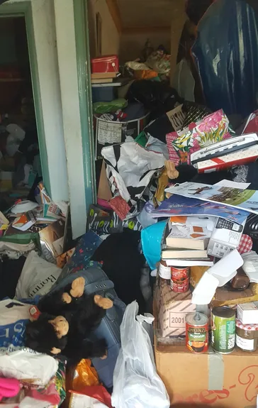 Völlig zugestellter Abstellraum mit Tüten, Kartons und Kleidung vor der Räumung