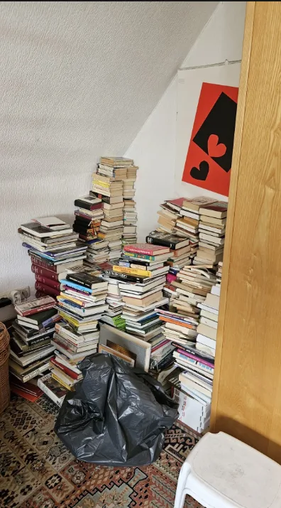 Dachschräge mit hohen Bücherstapeln und Müllsack vor der Räumung